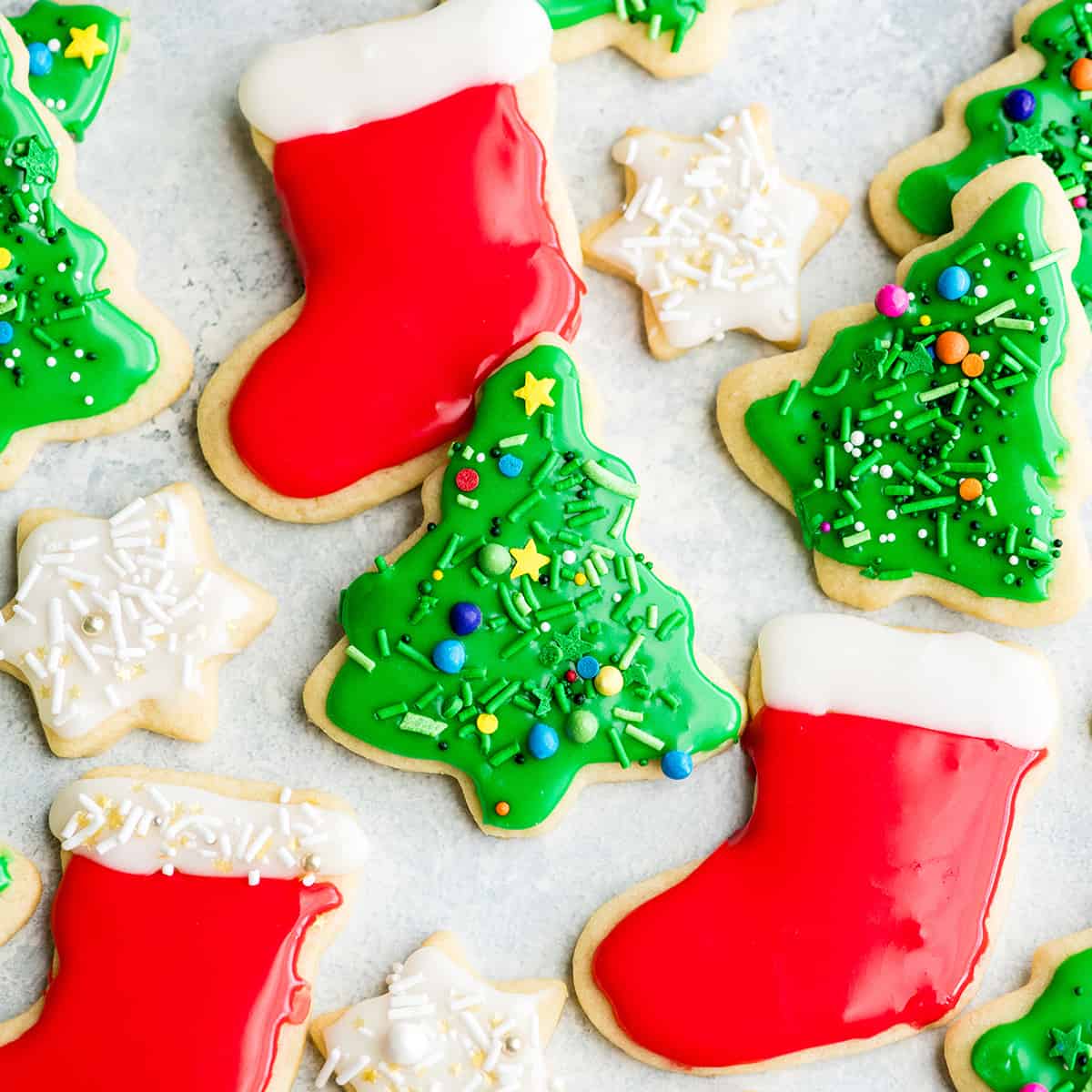 overhead view of Cut Out Sugar Cookies laying flat on a surface. Two green Christmas trees, two red and white stockings and two white stars with sprinkles. 