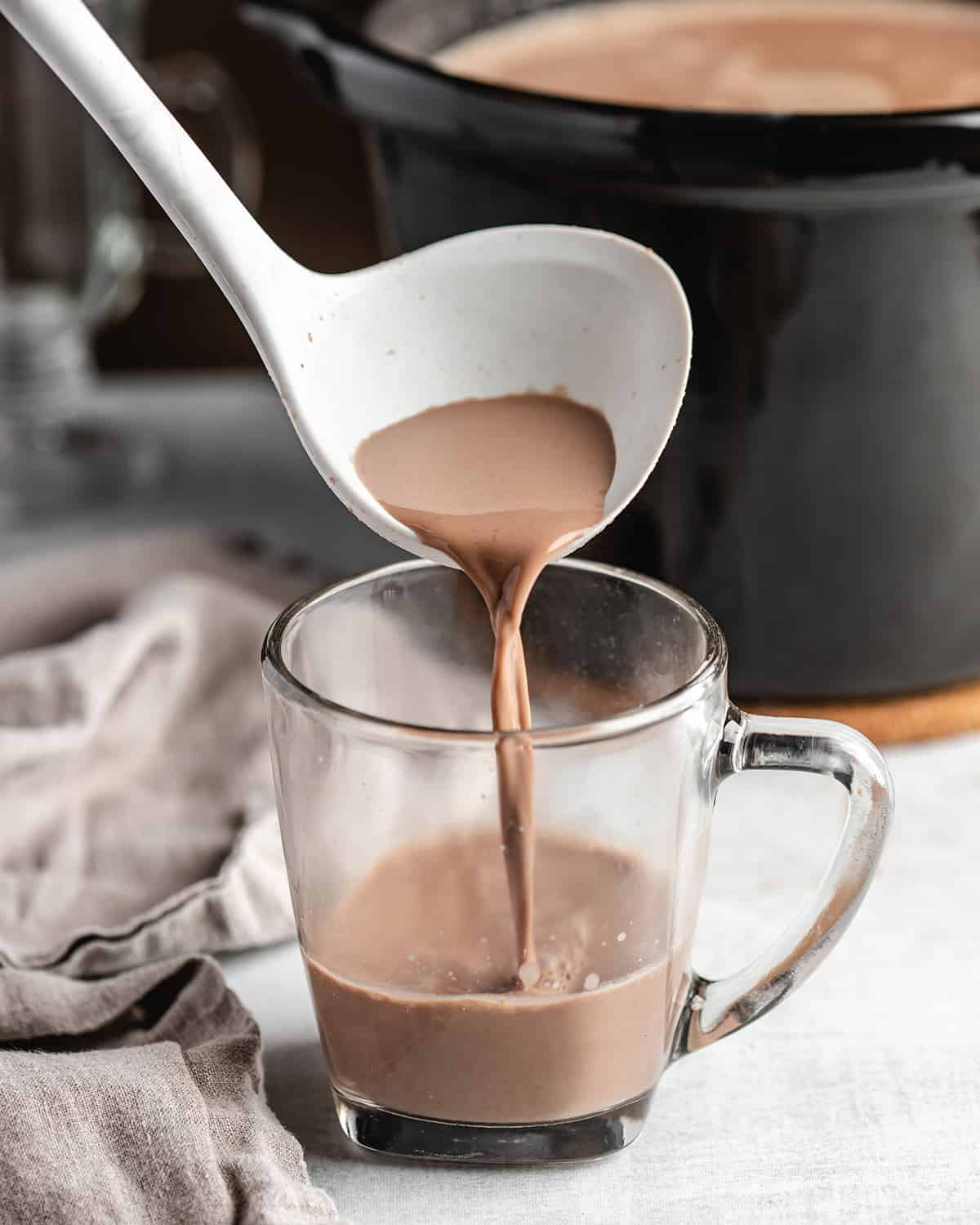 a ladle pouring Crock pot Hot Chocolate into a glass mug