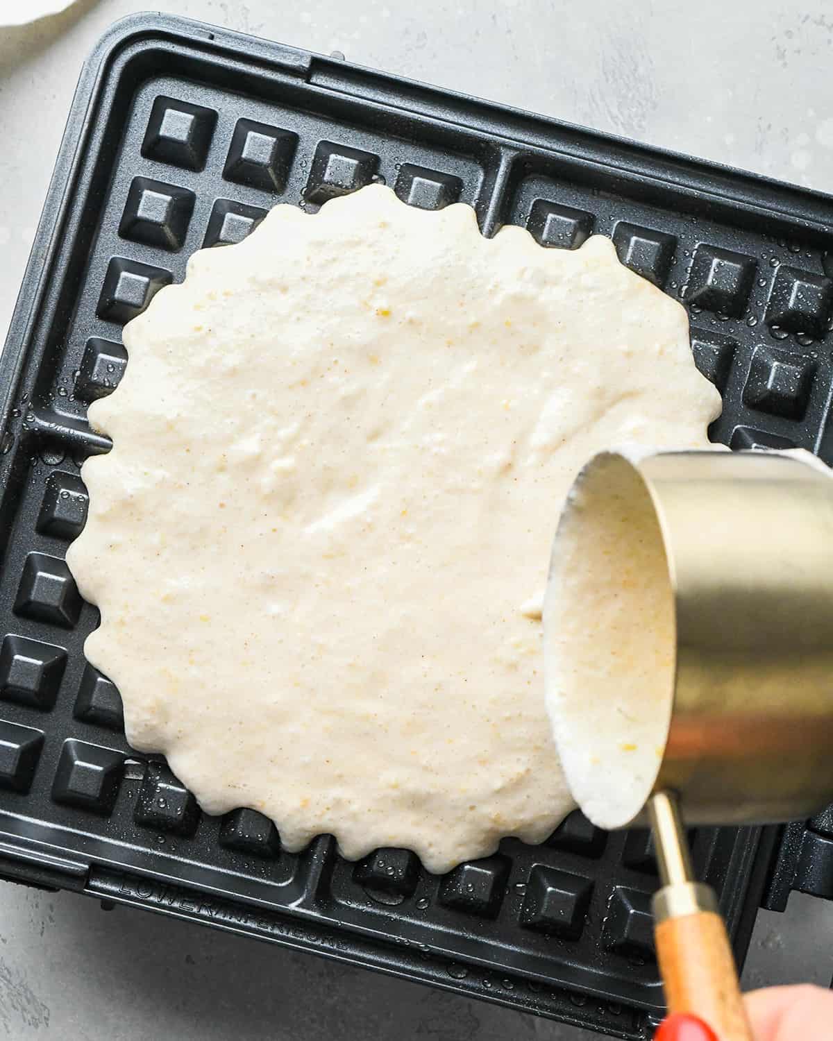 How to Make Waffles - waffle batter being poured into a preheated waffle maker