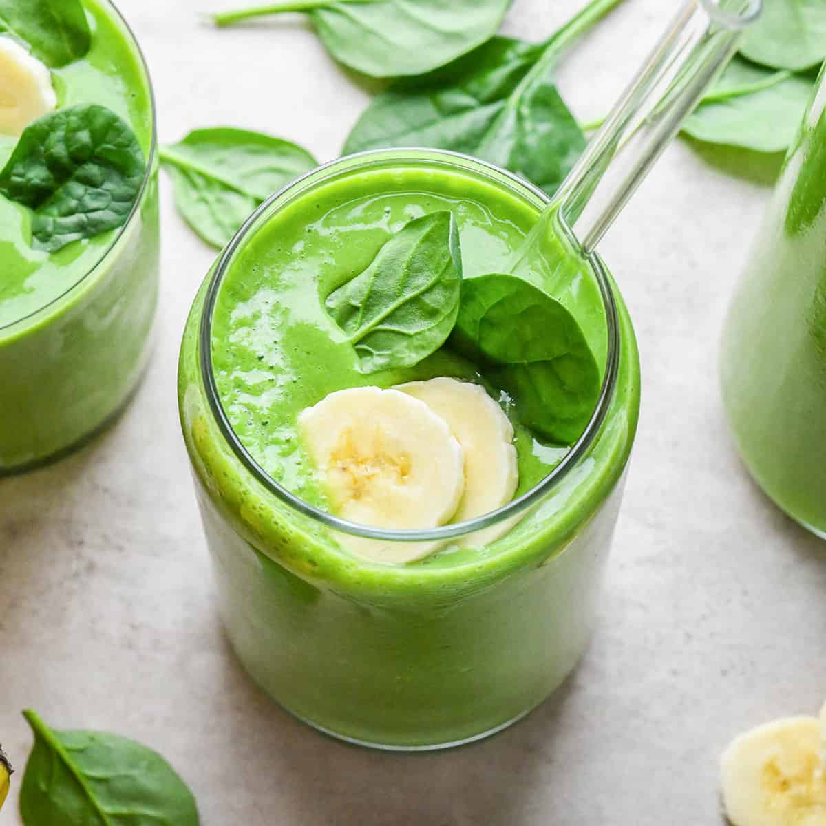 Spinach Smoothie in a glass with spinach and banana on top